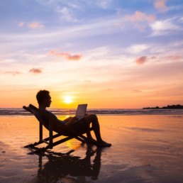 silhouette of happy business man with laptop working on the beach