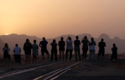 People staring at sunset in a dusty rocky environment