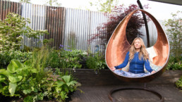 Woman meditating in a copper egg shaped garden chair